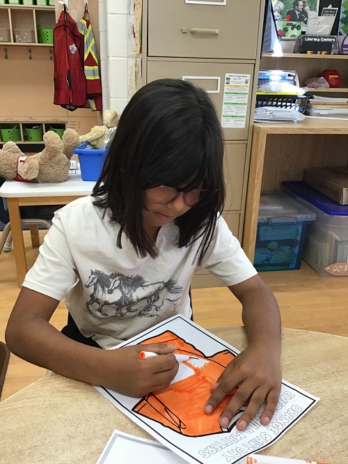 child colouring a picture of an orange tshirt