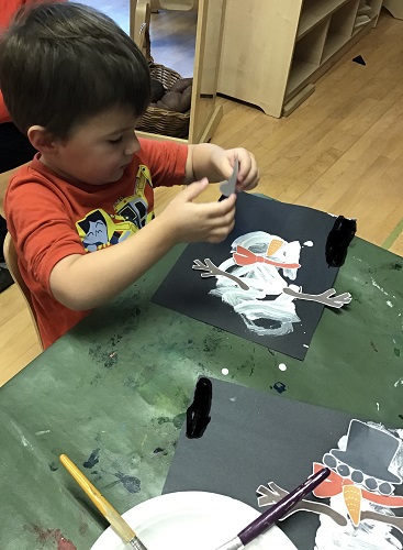 A child painting a snowman on paper