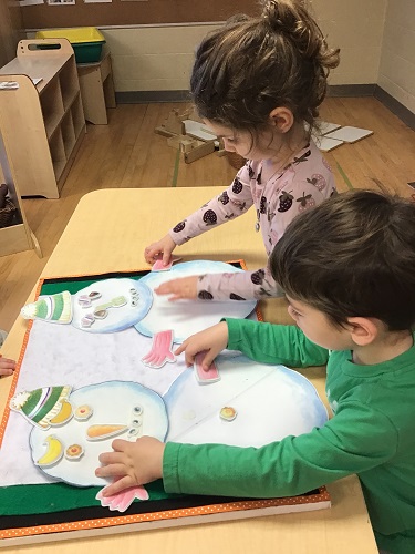 Two children decorating paper snowman