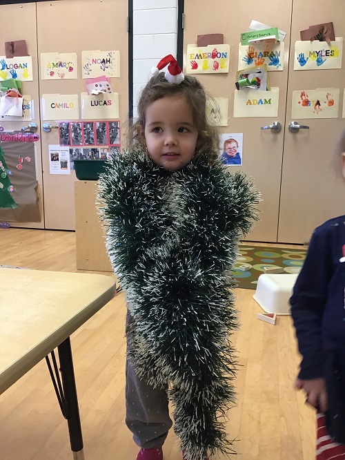 child dress as a christmas tree with green tinsel worn as a scarf