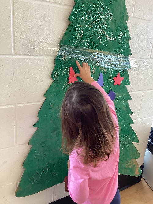 child decorating a cardboard tree cut out