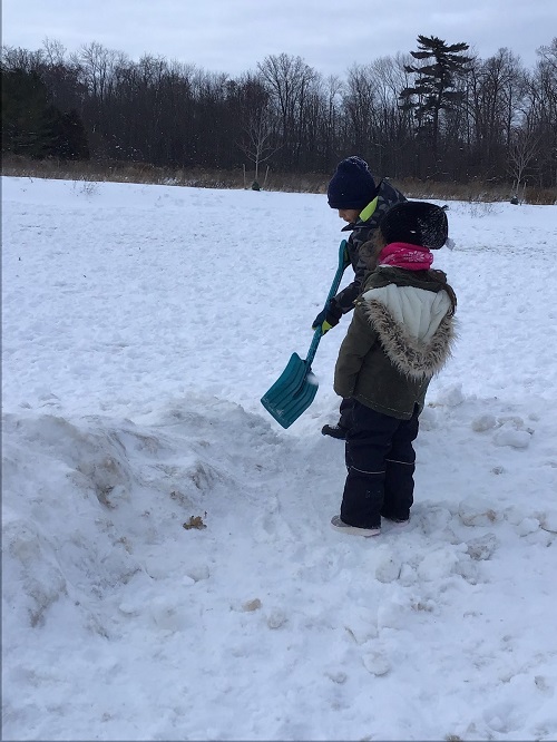 child standing in snow with a shovel