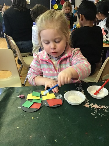 Child gluing red, green, and yellow squares