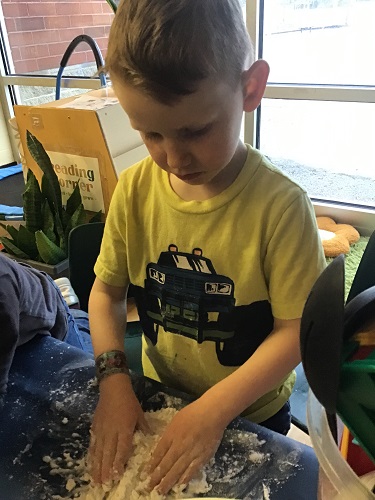 school age boy patting his dough