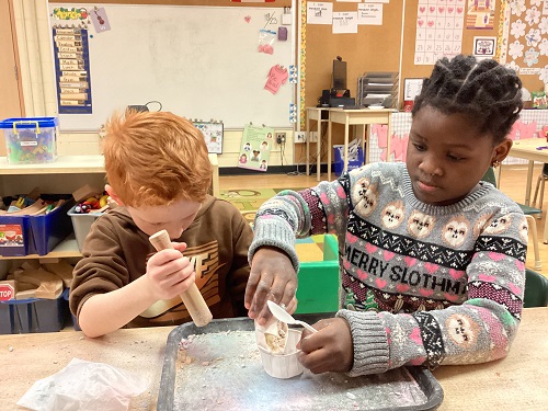 Two children using the mortar together