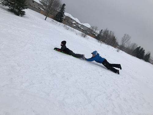 2 children sledding in skeleton format