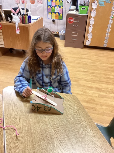 school age child with cardboard ramp and character on snowboard