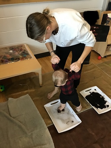 An educator helping an infant step into the water