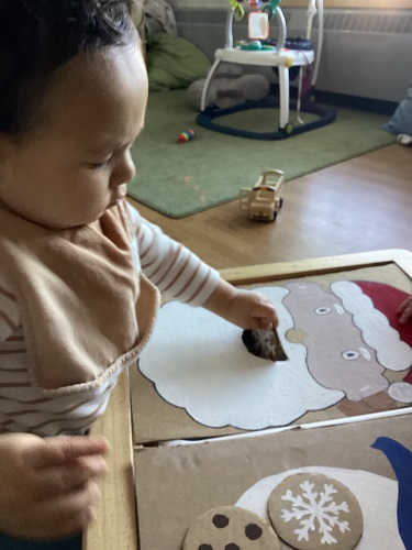 An infant feeding a cardboard Santa cookies