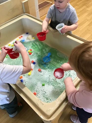 Children at a sensory table scooping water