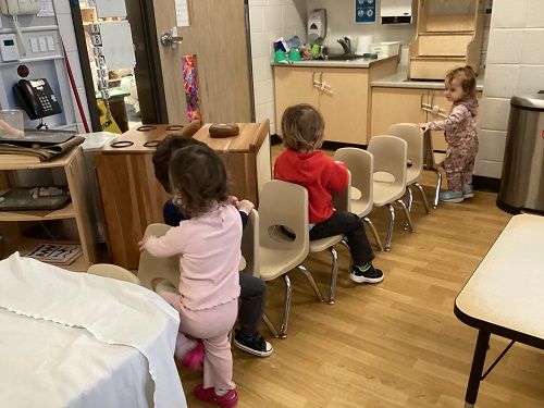 Children lining up chairs to sit on in the classroom