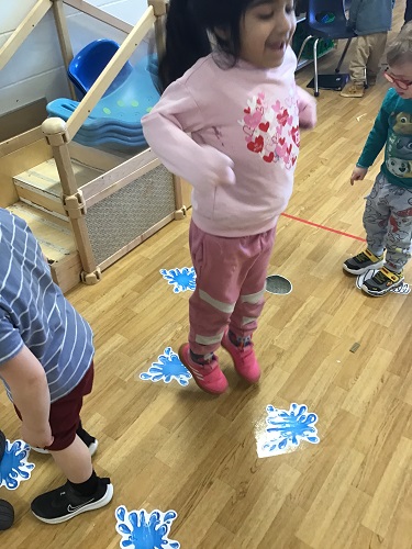 Children following the actions of the pictures on the floor