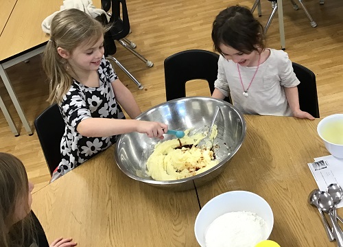 Children taking turns to add ingredients into a large bowl