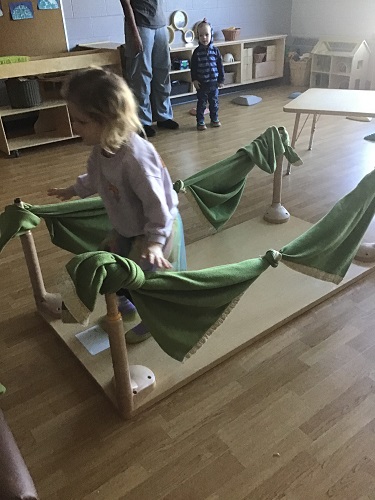 A child crossing a bridge made out of a table flipped upside down