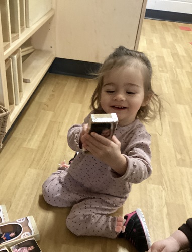 A child holding a block that has a photo of herself on it