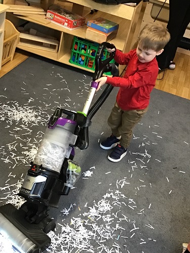 A child using a vacuum on the carpet in the classroom