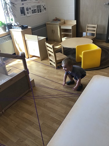 A child preparing to crawl through string attached to the table and climber