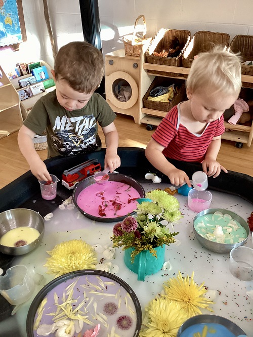 2 preschool children engaging in a sensory tuff tray experience