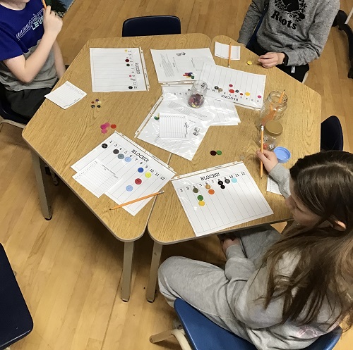 3 School Age 2 children sitting at the table with their Blocko charts, buttons, dice and pencils sitting waiting for the game to start