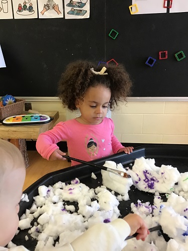 Toddler mixing snow in tuff tray