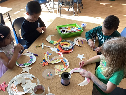 A group of school age students working on getting creative on paper moons