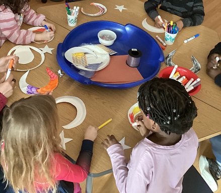 A group of school age children getting creative with paper moons and stars