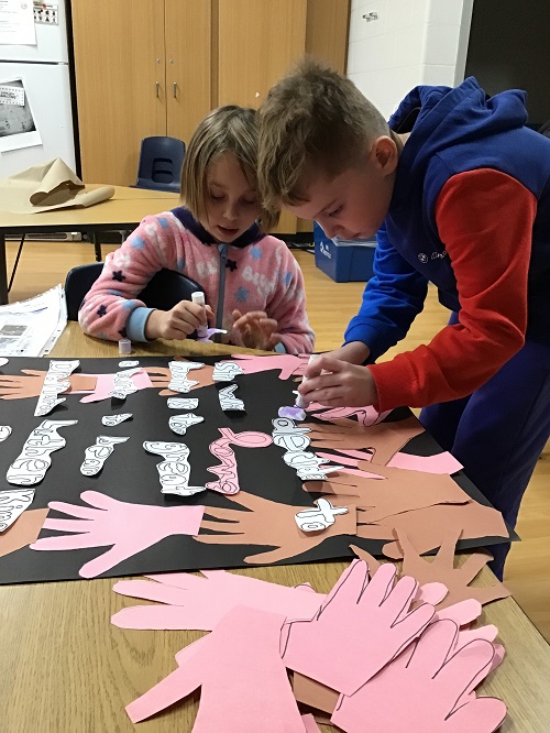 2 school age children working on a collaborative art poster highlighting Black History Month