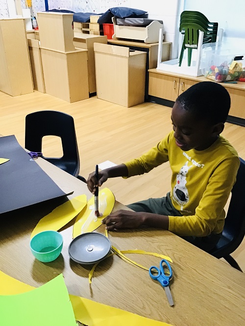 A school age child working on gluing for an art project