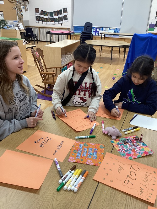 3 school age children sitting at a table creating their 2026 posters