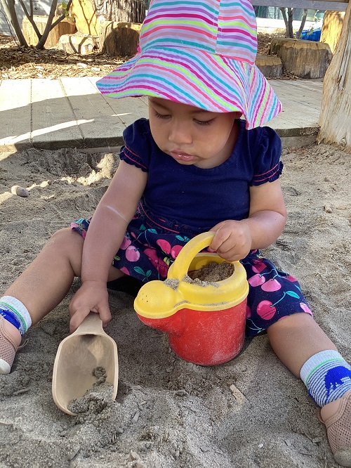A toddler child exploring the sandbox