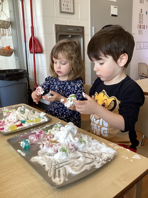 Two children exploring with shave foam and loose parts.