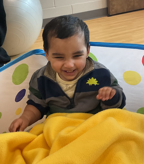 child laughing with yellow blanket