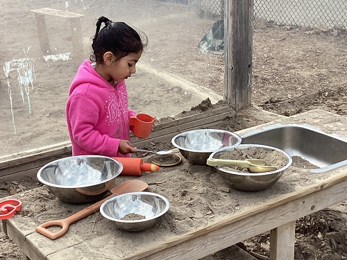 A child making Roti in the snad area