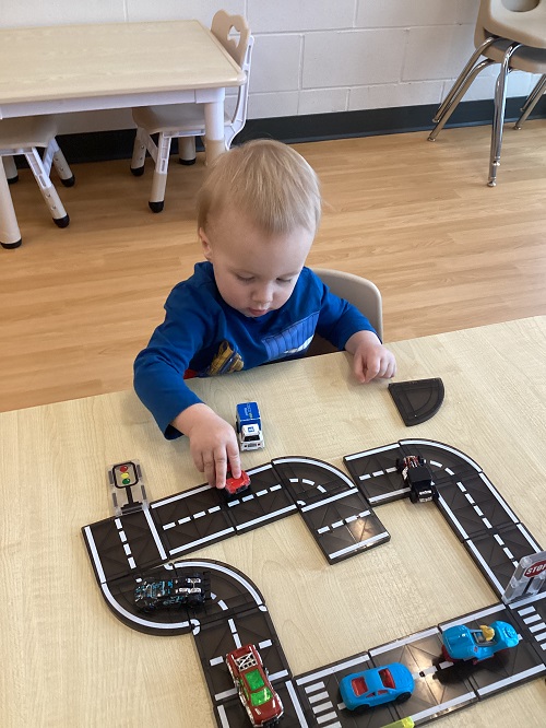 A toddler driving a car on a magnetic road