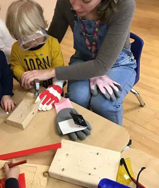 toddler and educator using a hammer