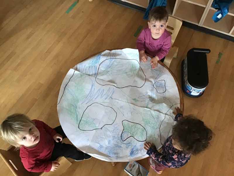 children colouring large globe on a paper