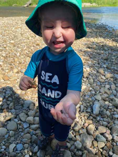 boy holding a bug outside by the water