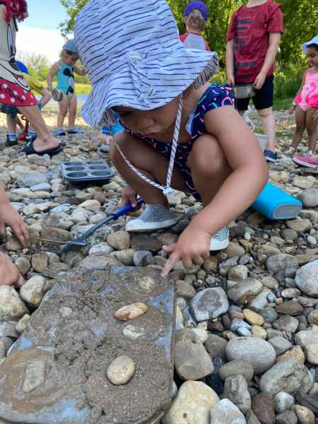 children observing and digging in a natural ground of stones