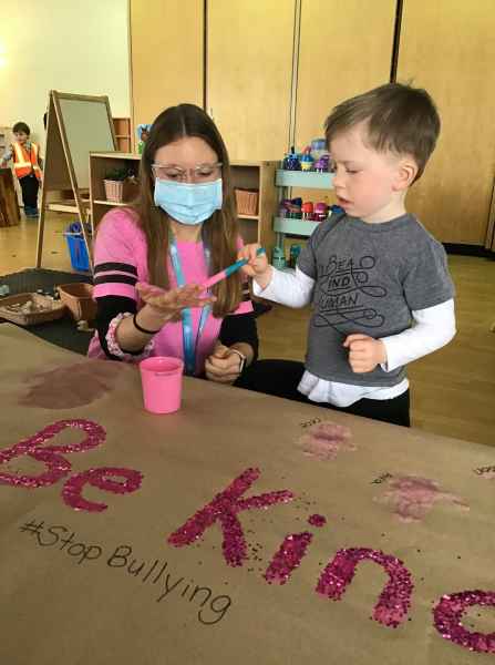 boy painting educators hand to make handprints