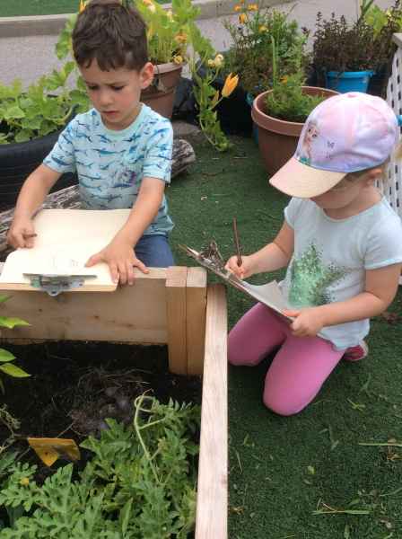 children drawing bunnies on a paper attached to a clipboard outside