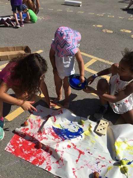 toddler and school-age child getting messy with paint outdoors