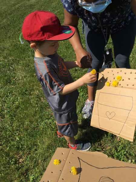 putting dandylions through holes in a decorated cardboard box