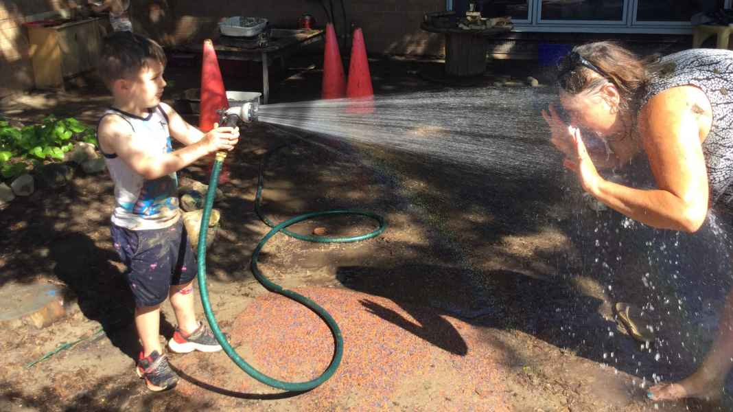 child spraying educator with a hose