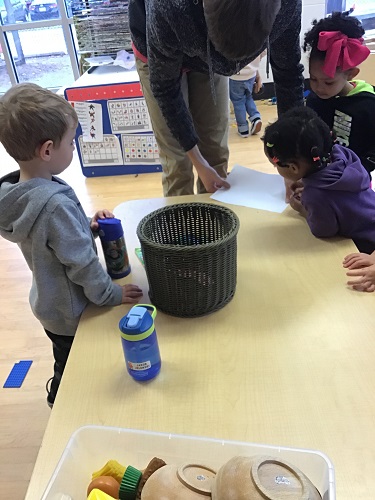 A group of children and an educator looking at a spider on a piece of paper