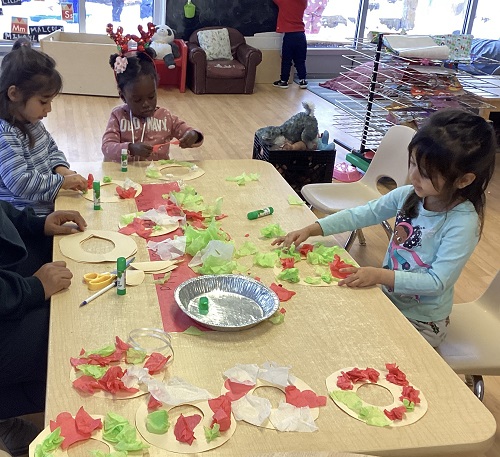 children sitting around a table doing some christmas themed crafts