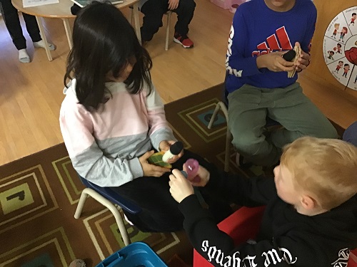two children sitting face to face showing the objects in their hands