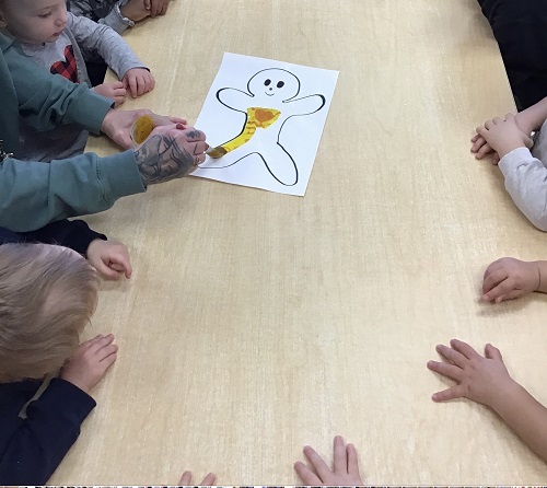 children around a table colouring a diagram on a person