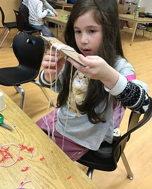 child holding up a cardboard craft creation