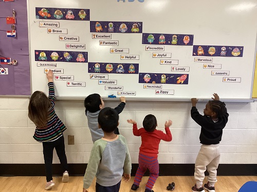 children looking at a white board with kind words on them