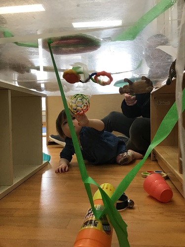 child under table reaching for object